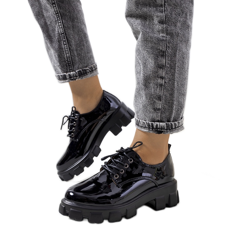 Sapatos lacados pretos em uma sola de trator Vento