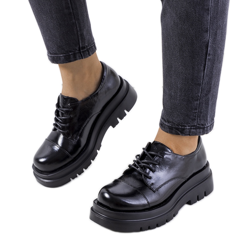 Sapatos pretos em uma sola de trator de Henta