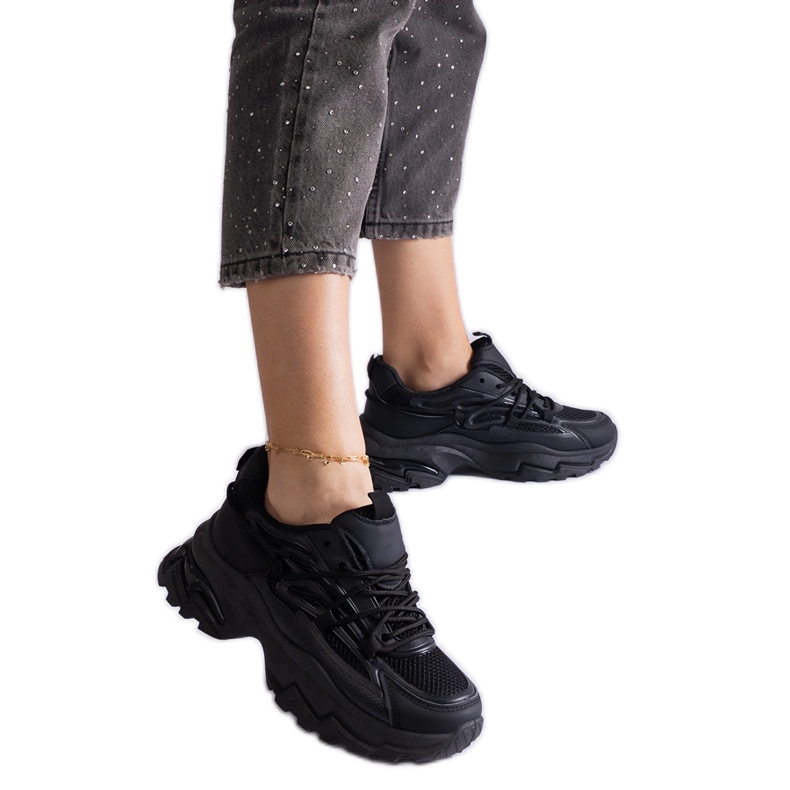 Tênis esportivos negros em uma sola enorme preto