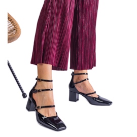 Bombas pretas envernizadas em um post com fivelas preto