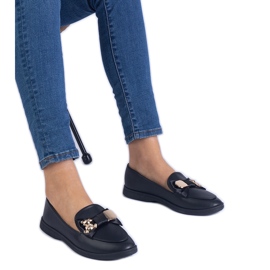 Mocas pretos decorados com um arco e um ursinho de pelúcia dourado