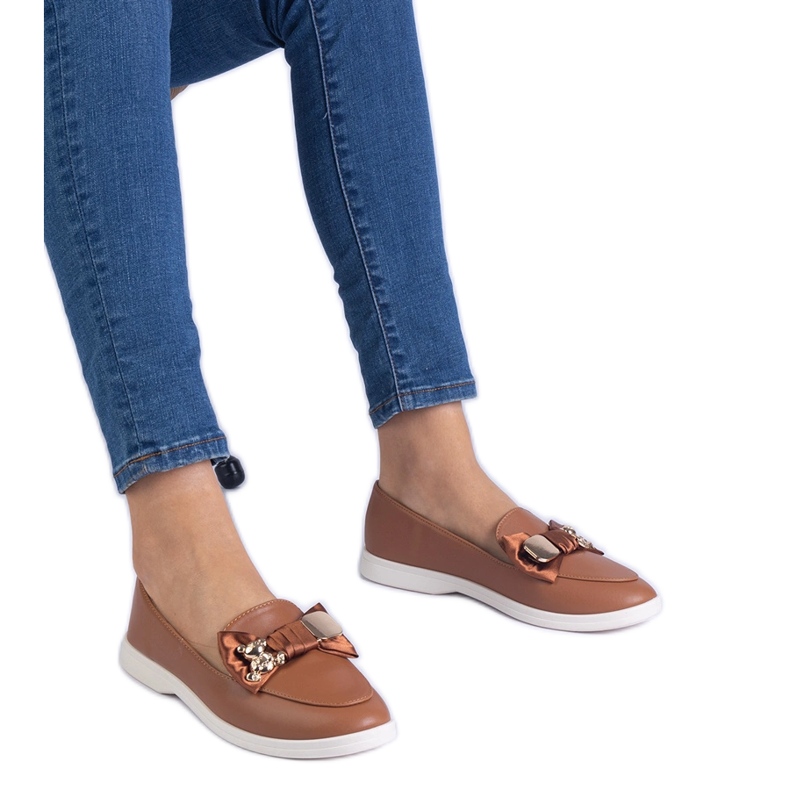 Mocas marrons decorados com um arco e um ursinho de pelúcia dourado castanho