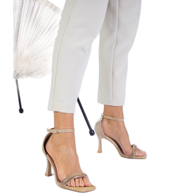 Sandálias elegantes douradas em um salto alto decorado com zircões dourado