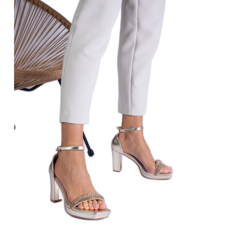 Sandálias elegantes douradas no pilar com zircões dourado