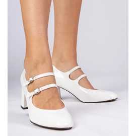 Bombas de mulheres brancas no pilar com fivelas branco