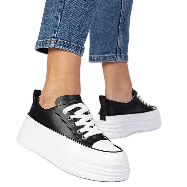 Tênis de mulheres pretas e brancas em uma sola alta branco