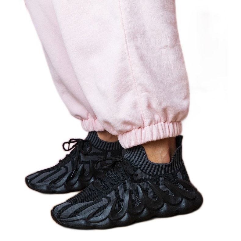 Tênis esportivos negros em uma sola enorme preto