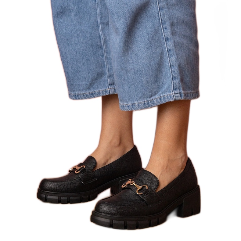 Sapatos pretos em um post baixo com uma decoração de ouro