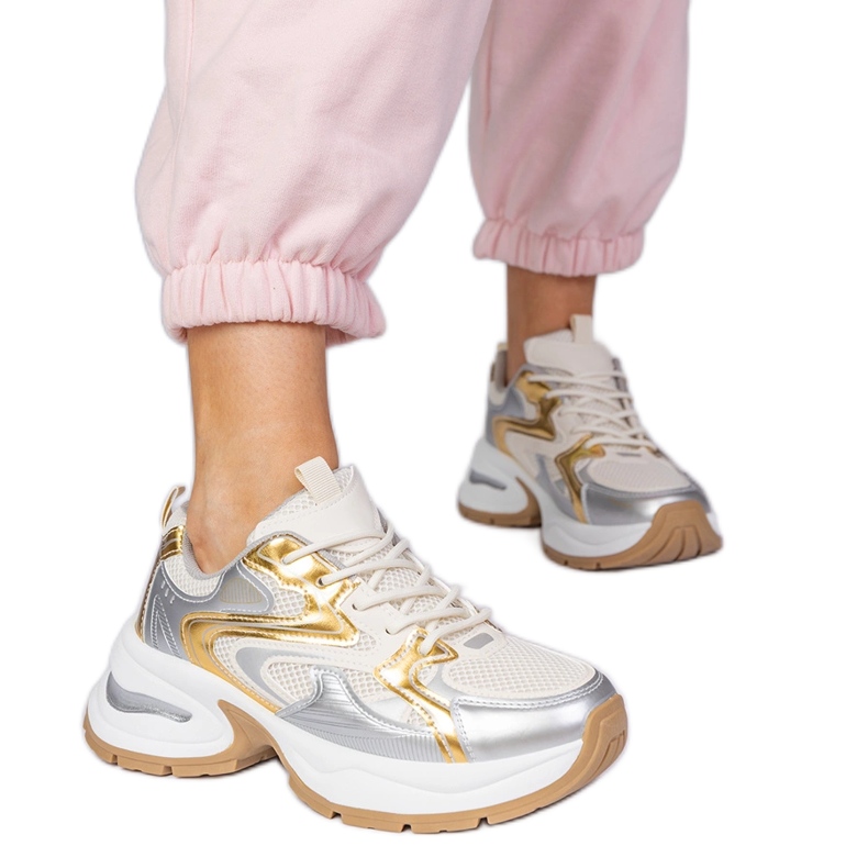 Tênis de esportes dourados em uma sola grossa