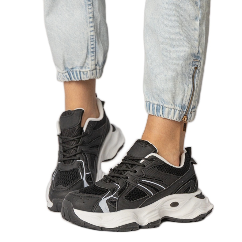 Tênis esportivos negros em uma sola enorme preto