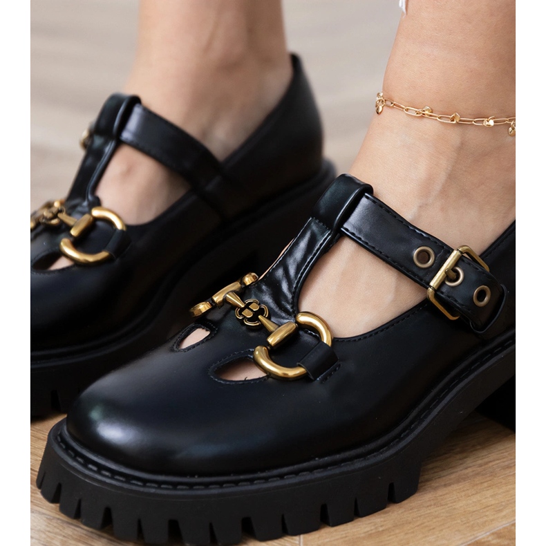 Sapatos pretos em uma sola grossa com uma decoração de ouro