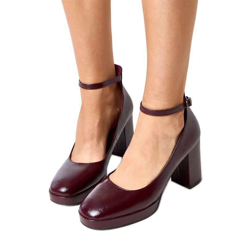 Bombas da Borgonha envernizadas em um enorme post de Batuma vermelho