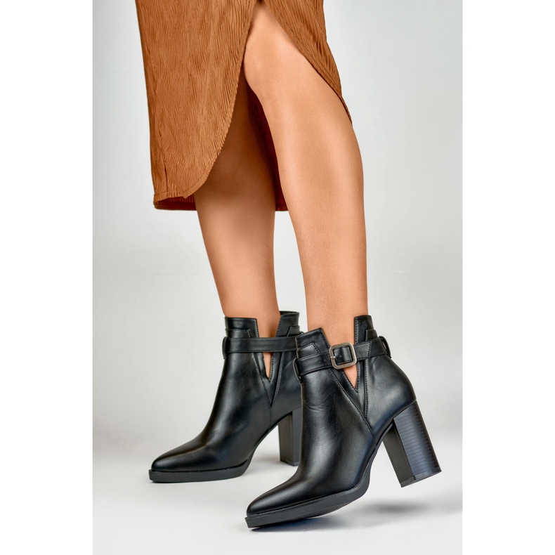 Botas pretas recortadas femininas em um poste bege 2