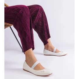 Bailarinas brancas com uma faixa elástica e um arco decorativo branco 1