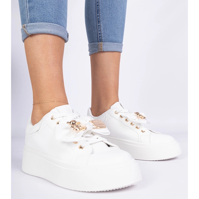 Tênis brancos decorados com um arco e um ursinho de pelúcia dourada 1