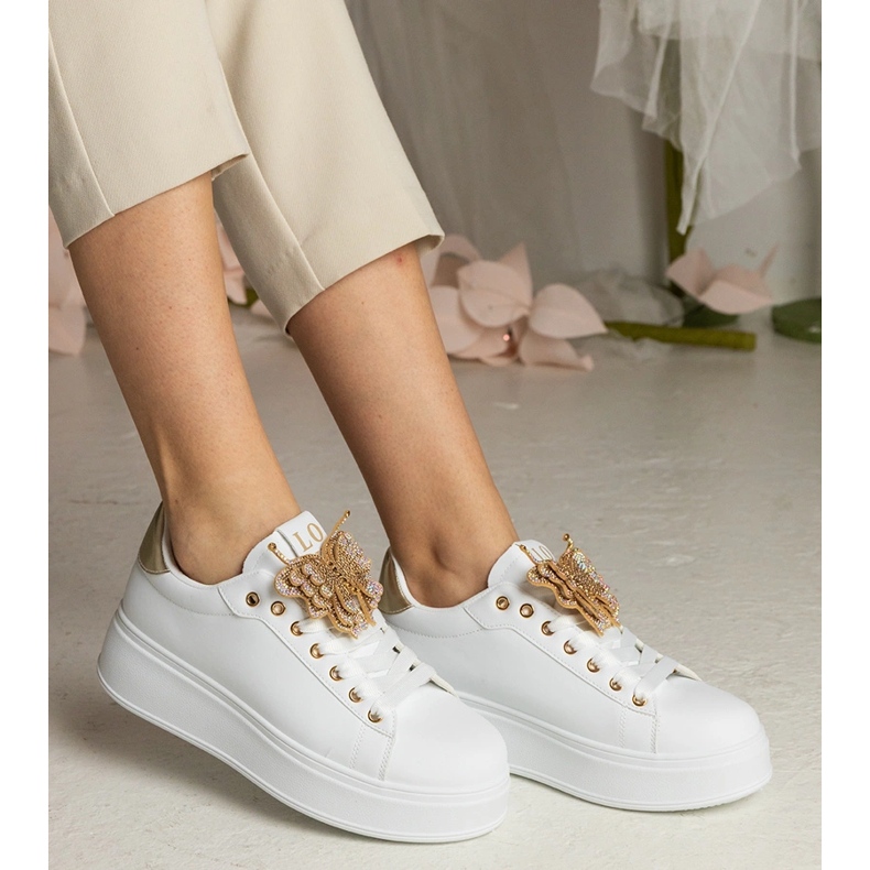 Tênis brancos e dourados decorados com uma borboleta com zircões 2