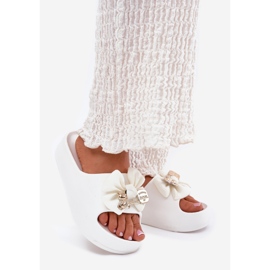 Chinelos de espuma feminina na plataforma com um arco e um broche branco 1