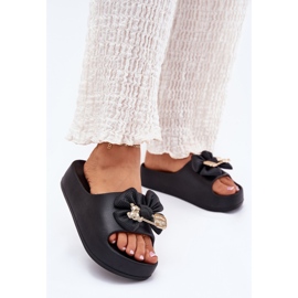Chinelos de espuma feminina na plataforma com um arco e um broche preto 2