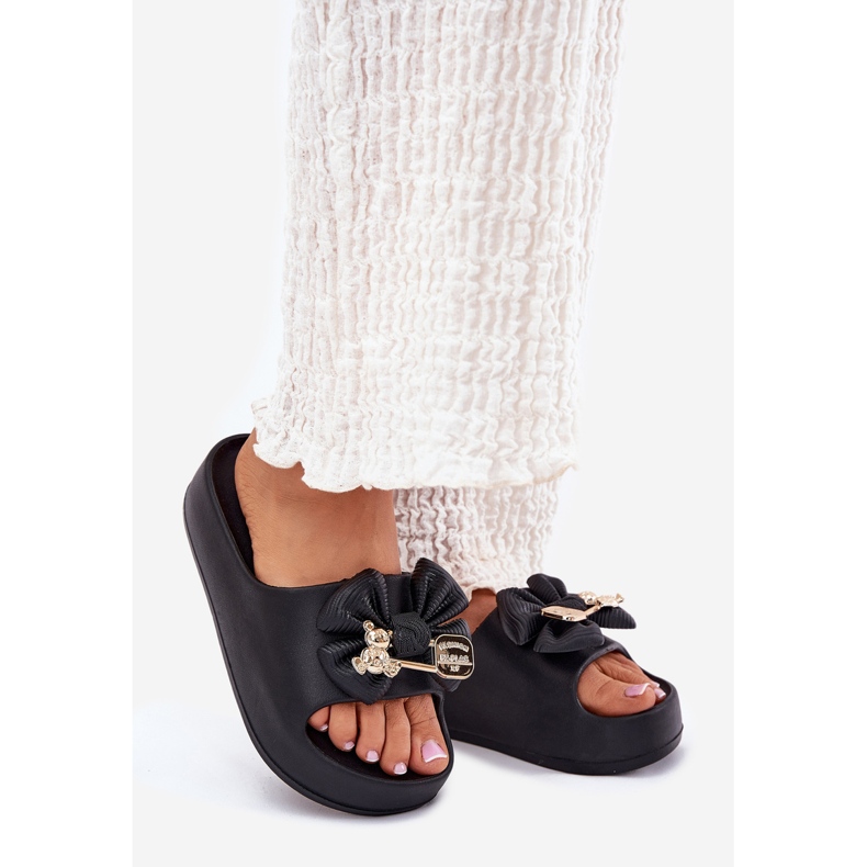 Chinelos de espuma feminina na plataforma com um arco e um broche preto 1